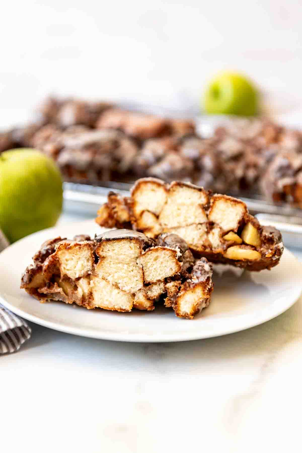 An apple fritter cut in half on a white plate.