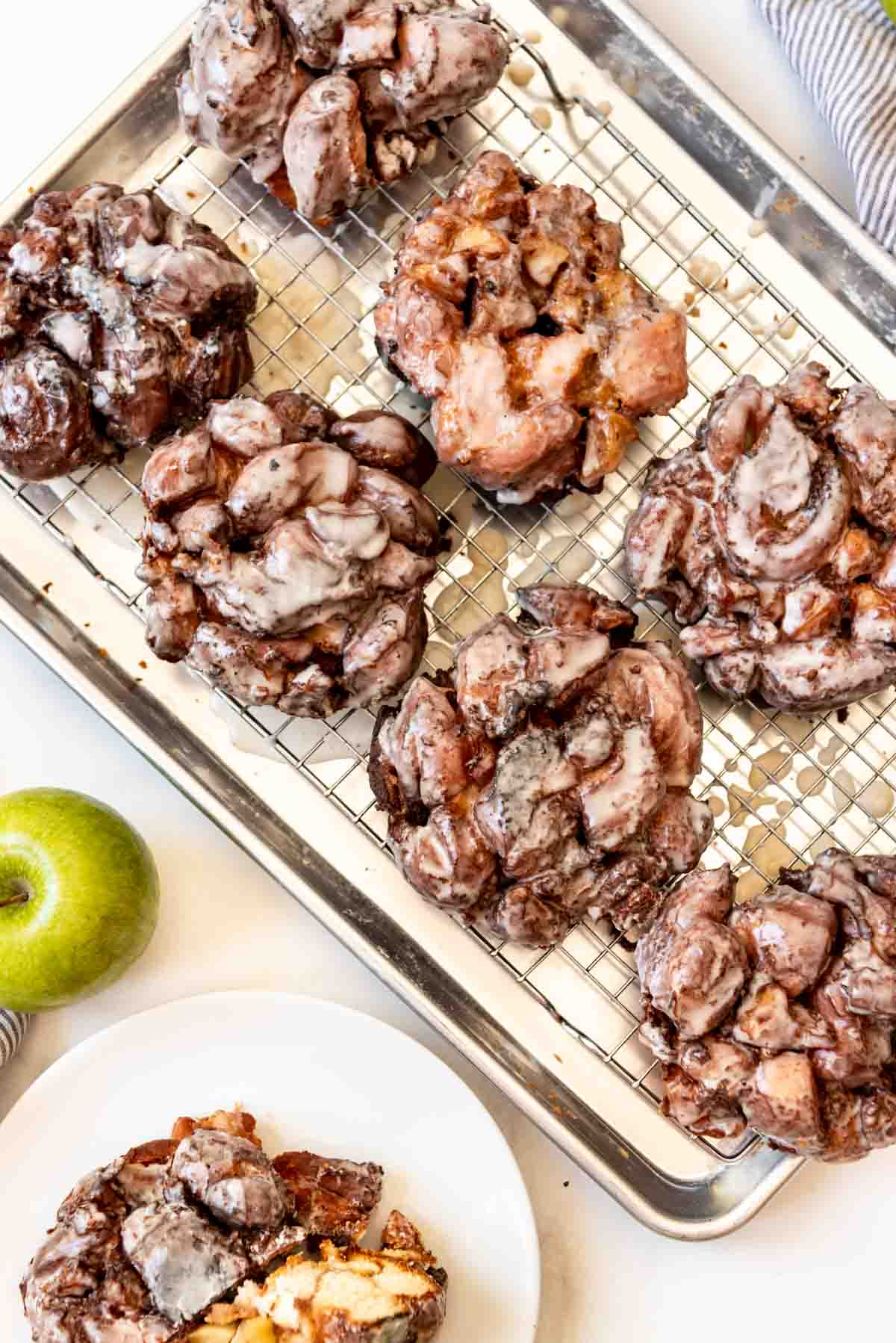 Glazed apple fritters on a wire rack.