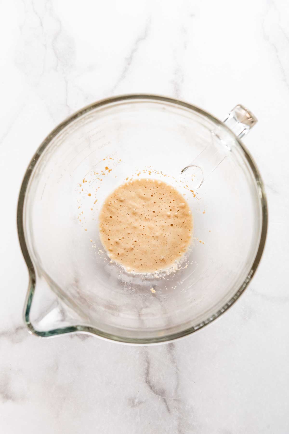 Yeast proofing in water in a glass bowl.