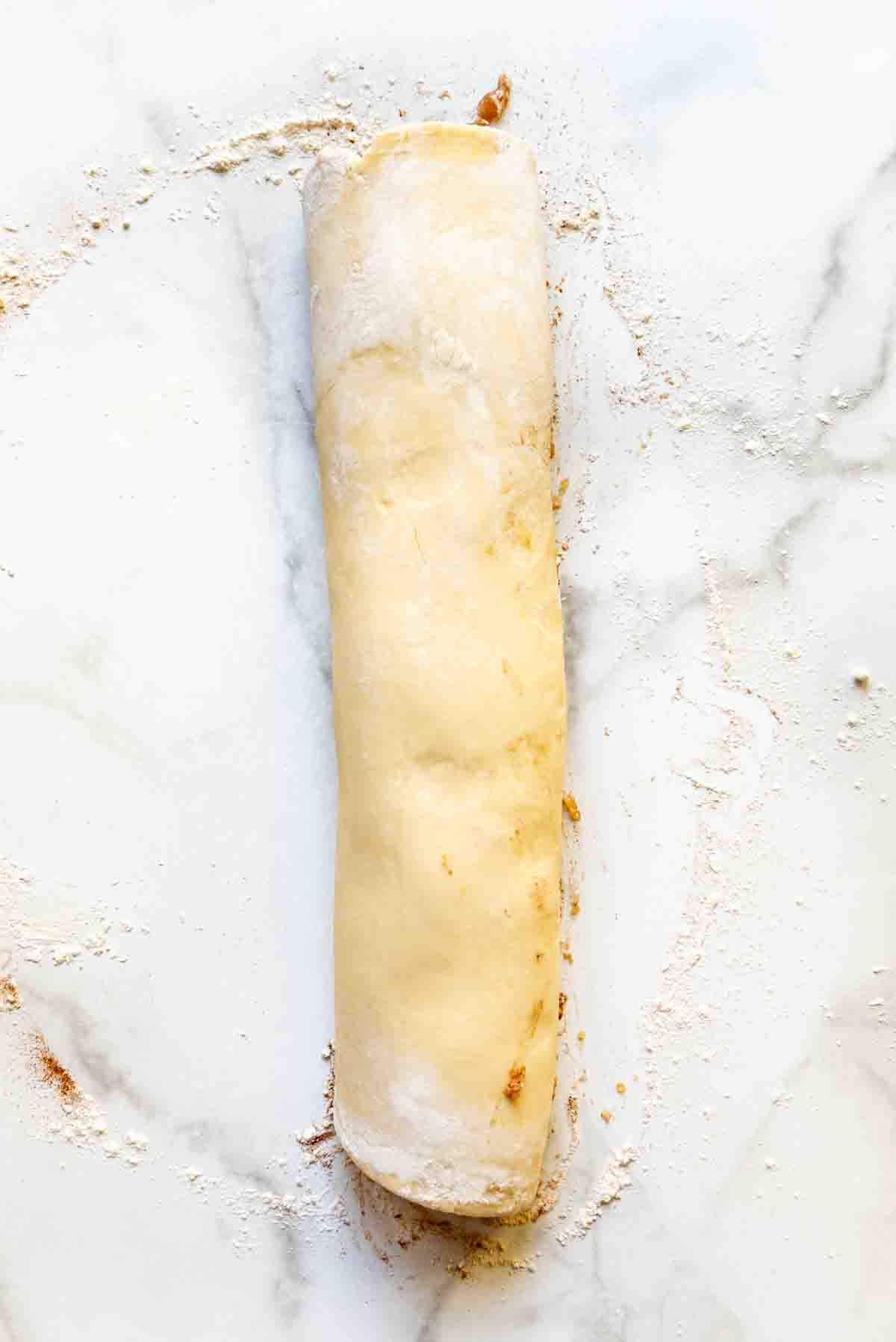 a rolled log of dough and apple filling for making apple fritters