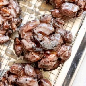 Glazed apple fritters on a wire rack.