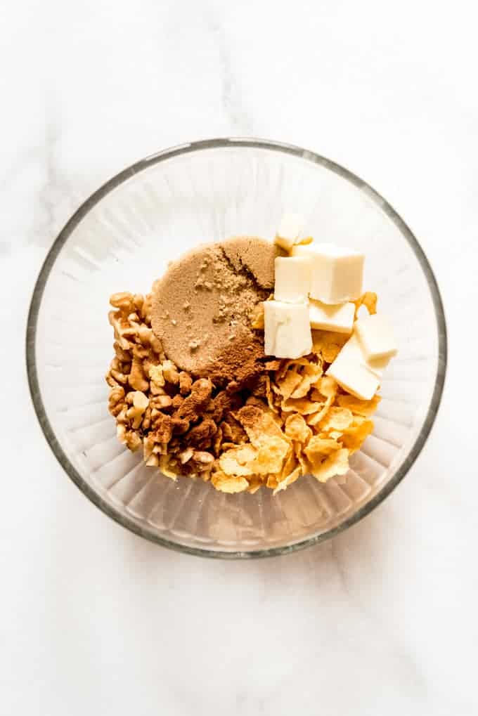 A glass bowl filled with cinnamon, walnuts, brown sugar, butter, and cornflakes.