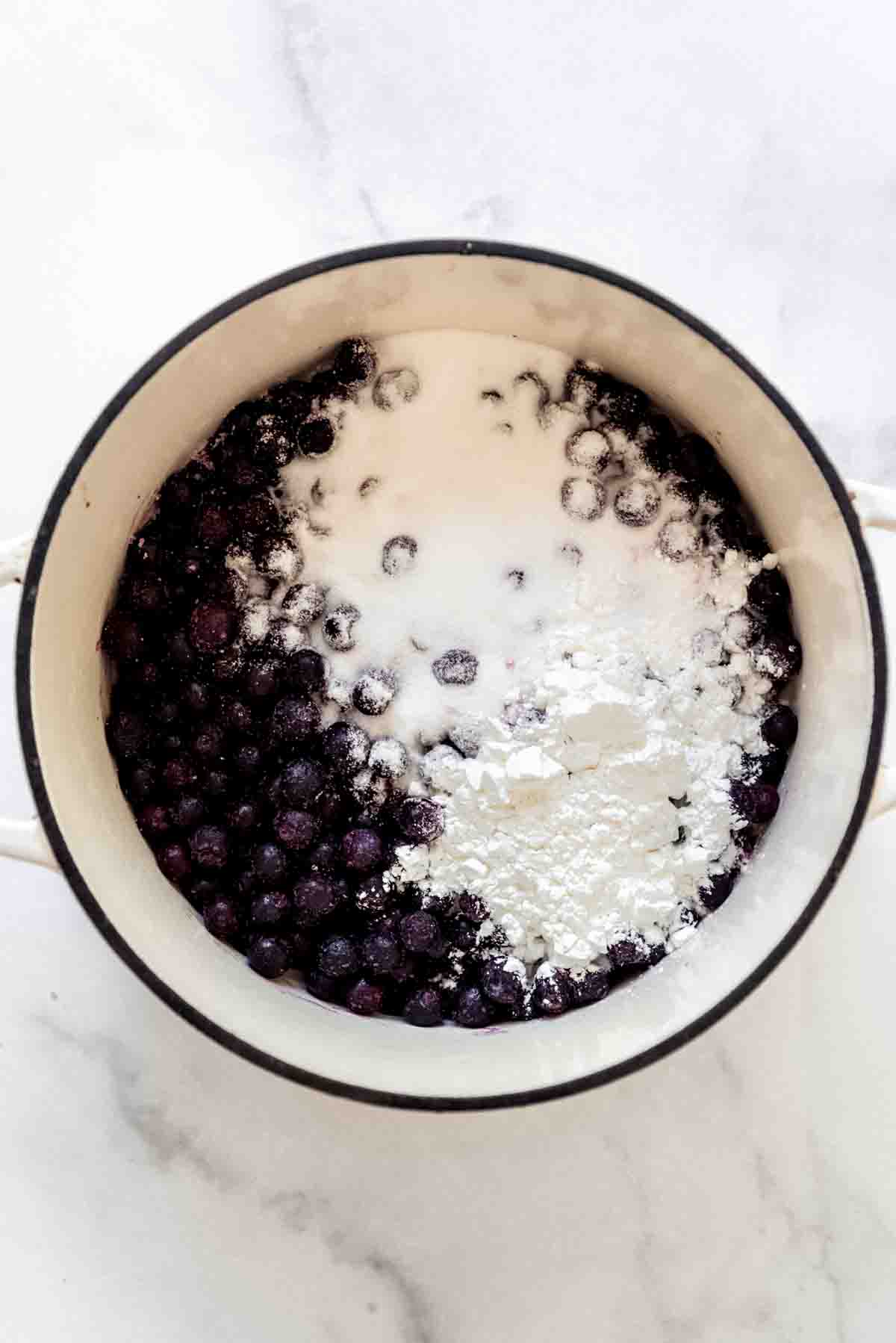 An overhead image of cornstarch, sugar, and blueberries in a pot.