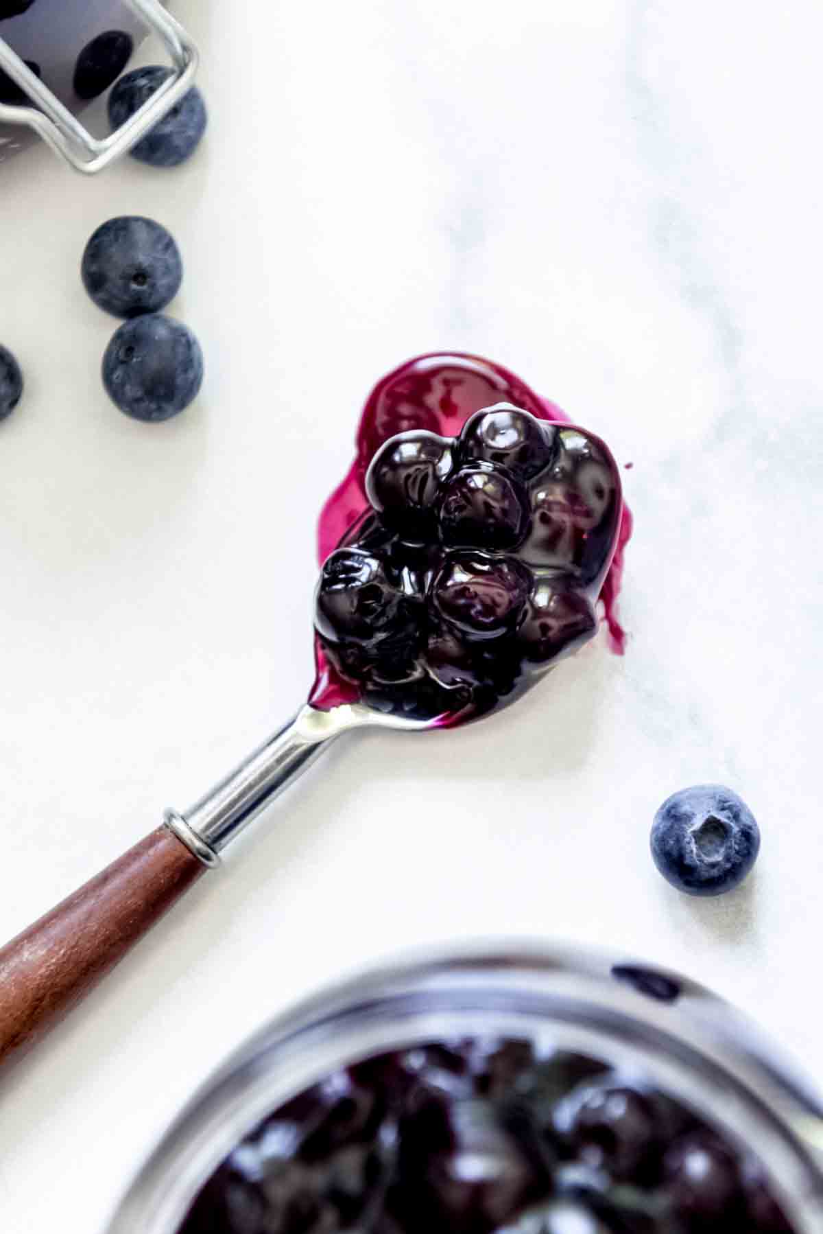 A close image of a spoonful of glossy blueberry pie filling.