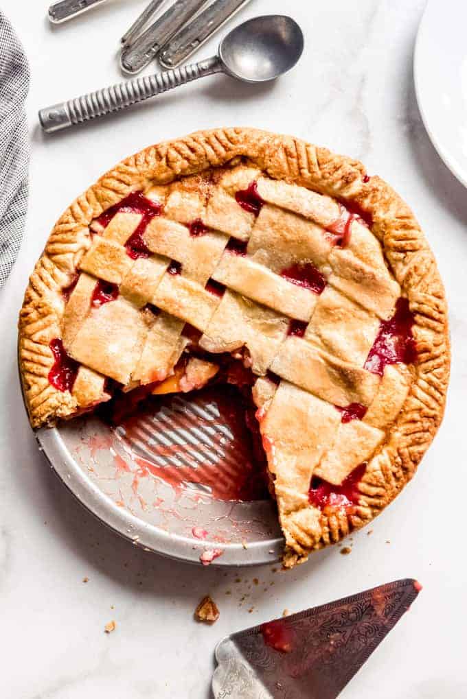 A raspberry peach pie with a lattice crust and a couple slices already cut out.