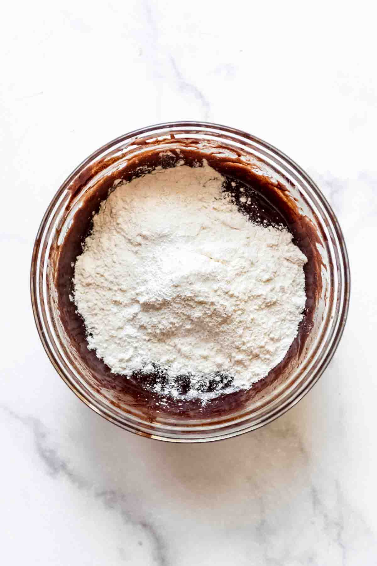 Flour and dry ingredients added to wet brownie batter.