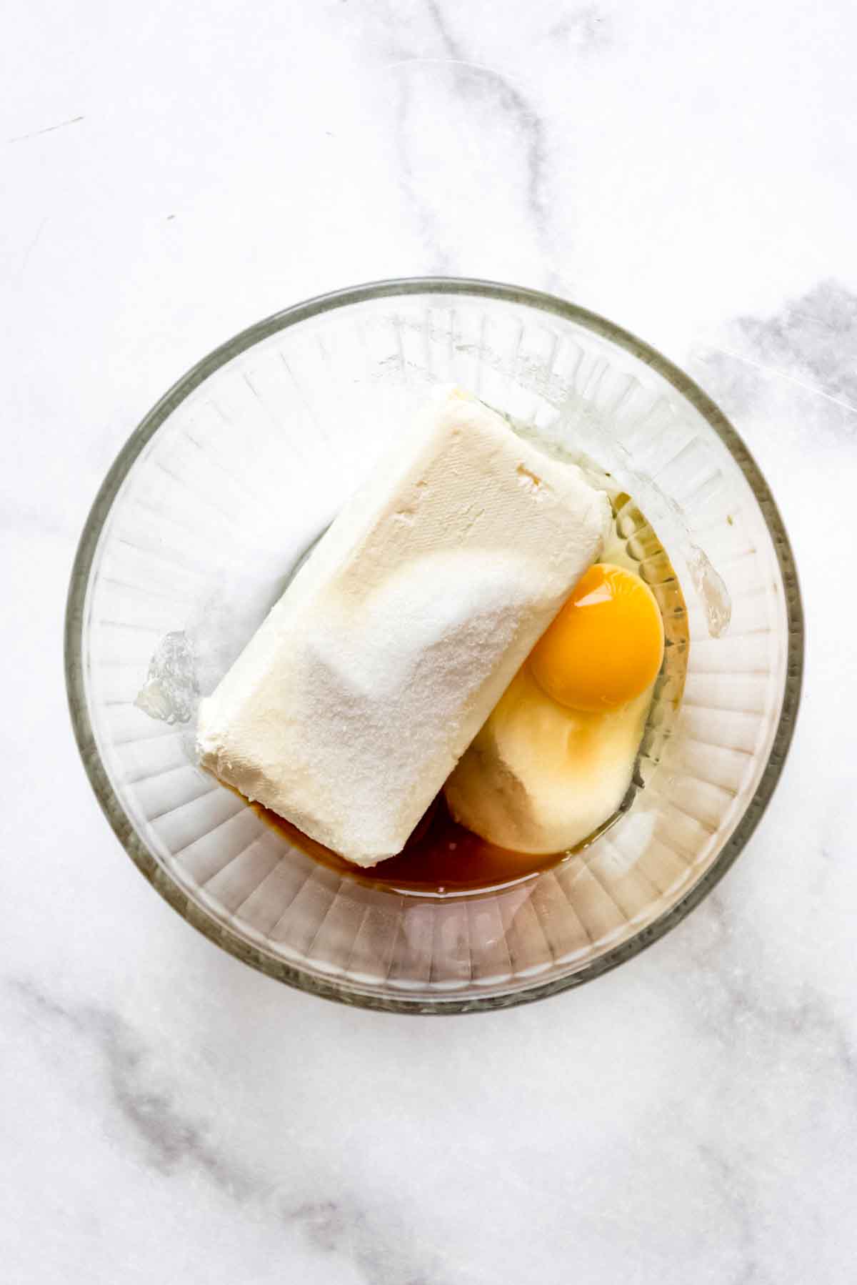 Cream cheese, sugar, and egg in a glass bowl.