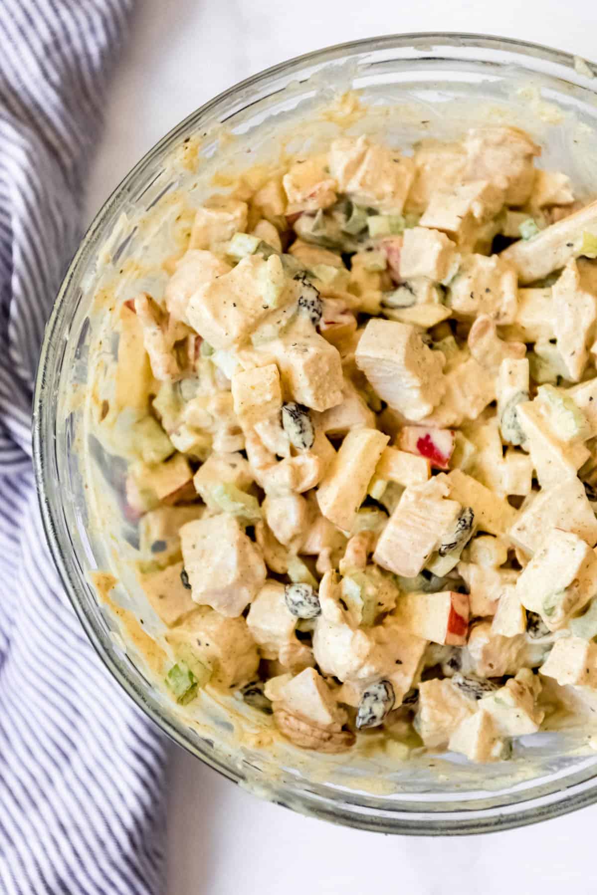 Overhead view of curried chicken salad in glass mixing bowl.