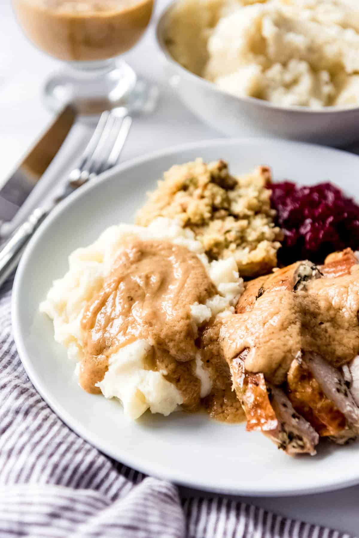 Close up of mashed potatoes, turkey, and gravy on a plate.