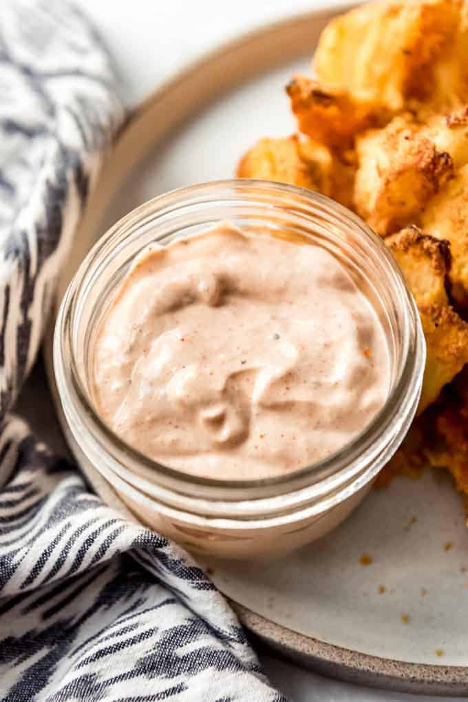 A side of blooming onion sauce served in a small mason jar on a plate
