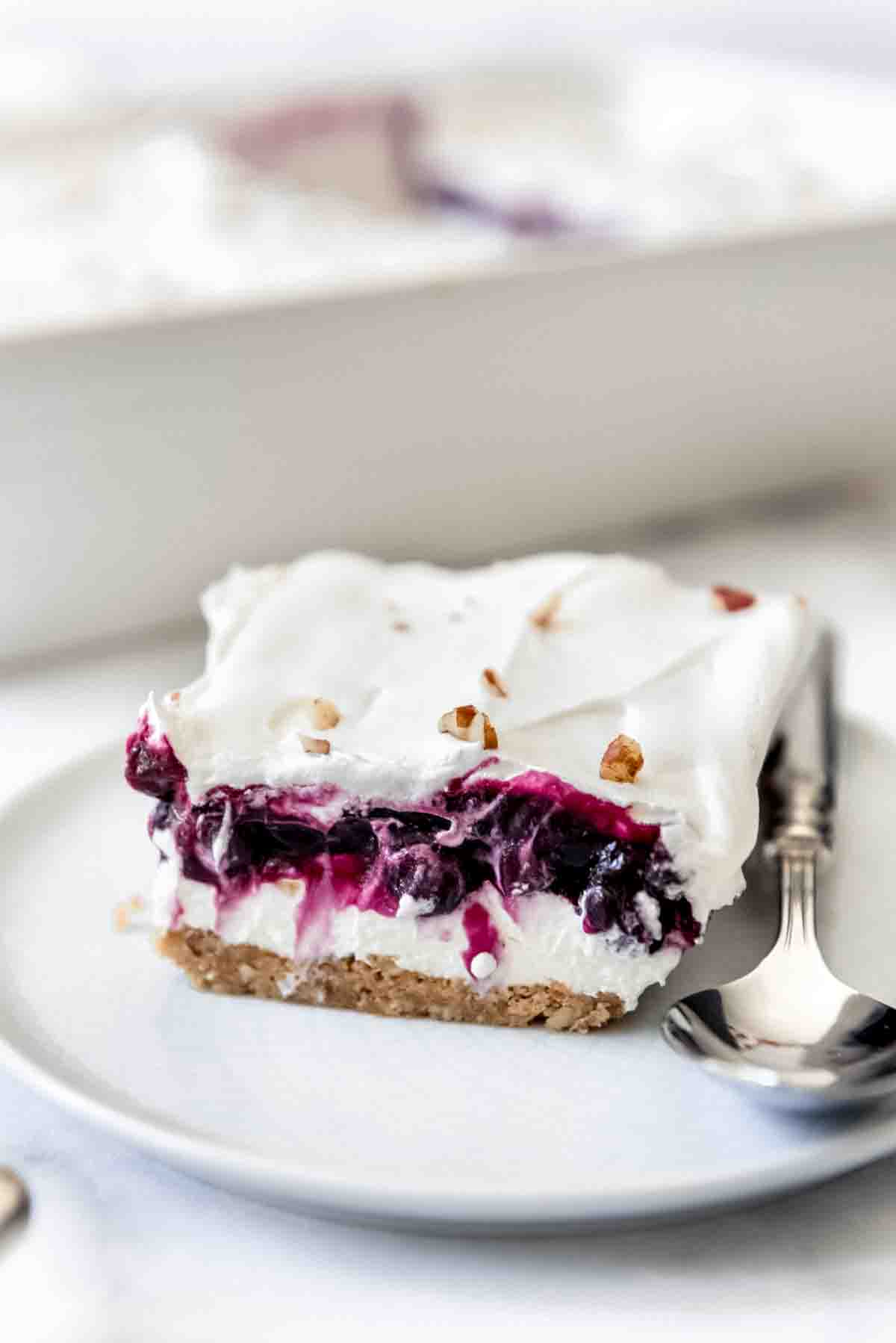 Layers of blueberry filling, whipped cream topping, and creamy filling on a plate.