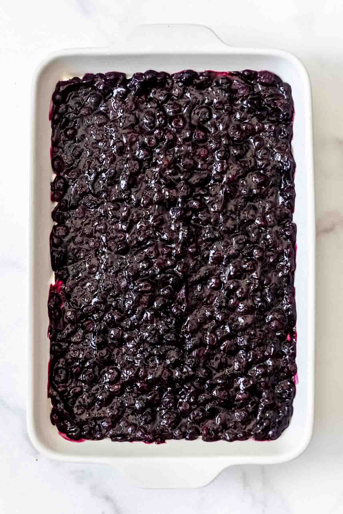 blueberry filling spread out in a white baking dish