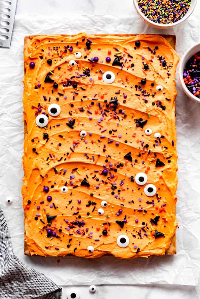 Tray of sugar cookie bars with orange frosting and sprinkles.