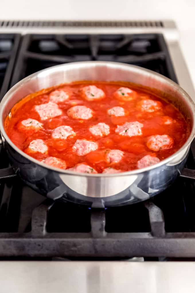 Meatballs simmering in a tomato sauce.