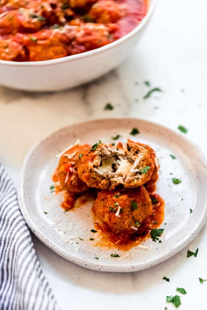 A meatball stuffed with mozzarella and cut open on a plate.