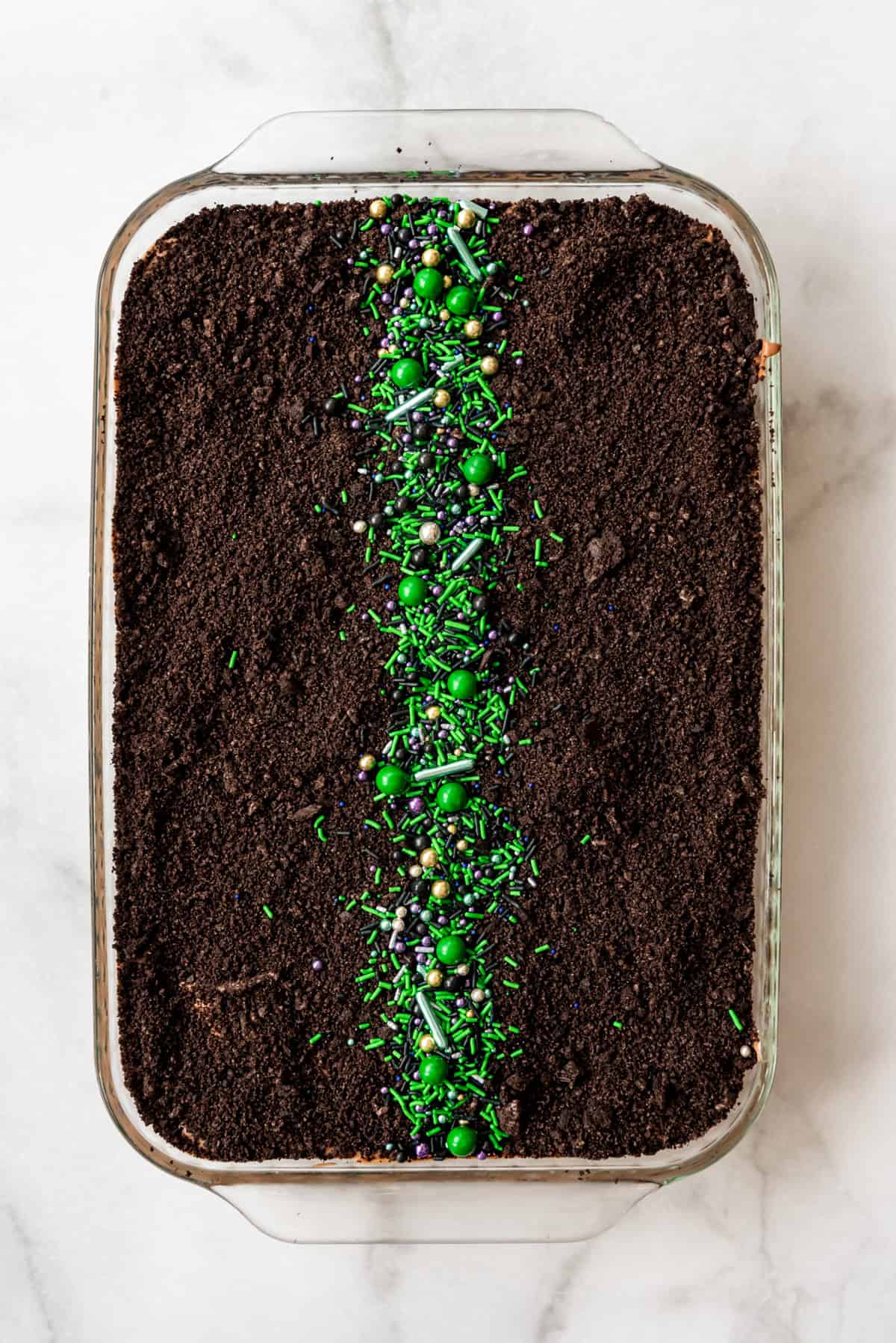 A row of green sprinkles on top of a dirt cake.