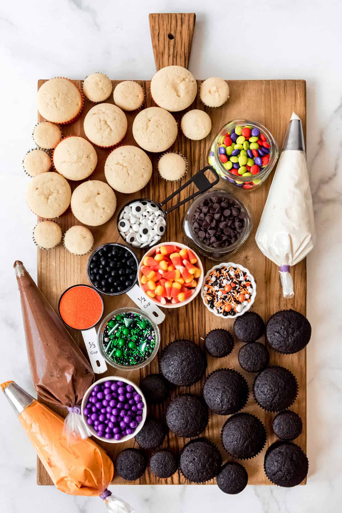 A DIY cupcake board with frosting, sprinkles, candy, and unfrosted cupcakes.