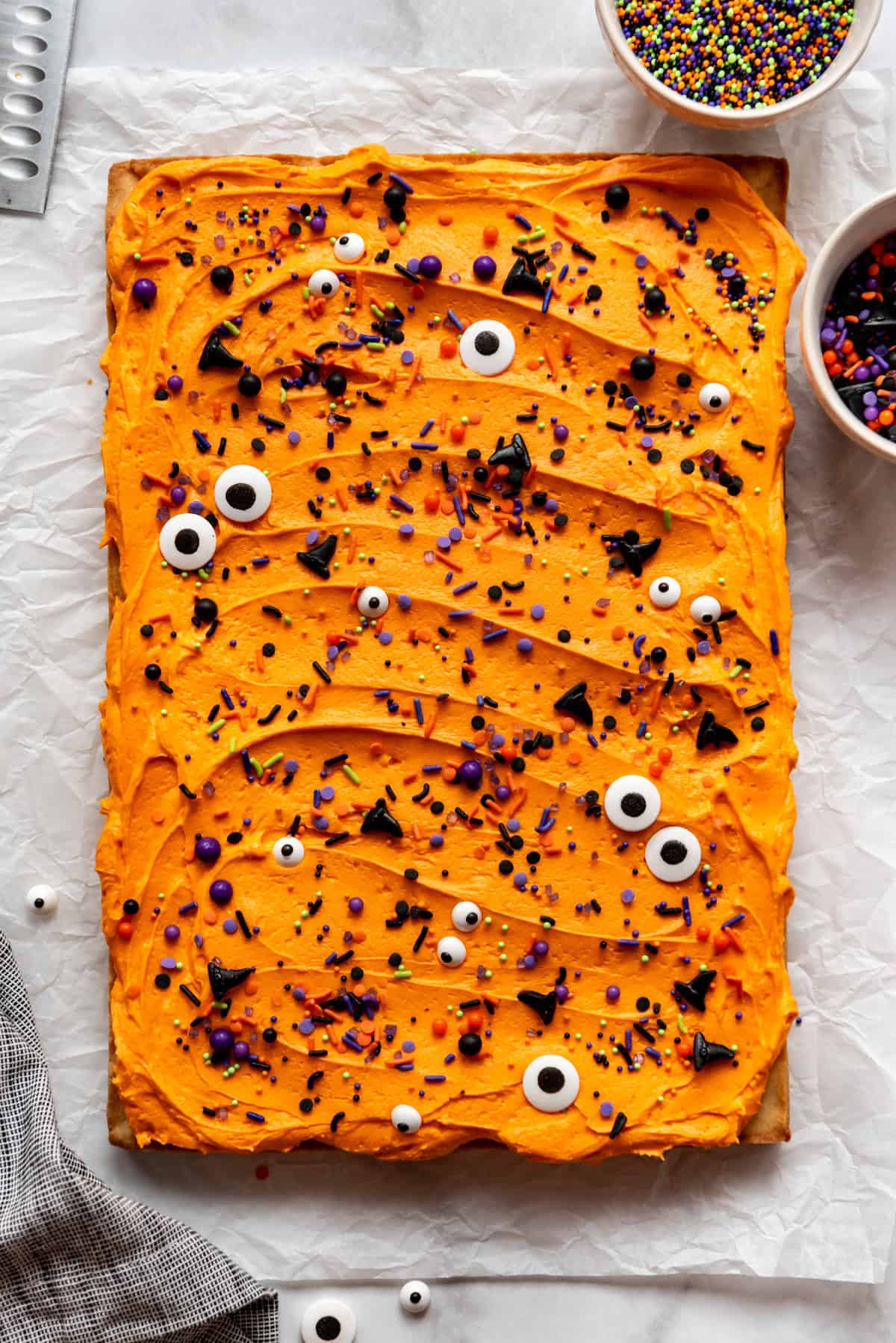 Tray of sugar cookie bars with orange frosting and sprinkles.