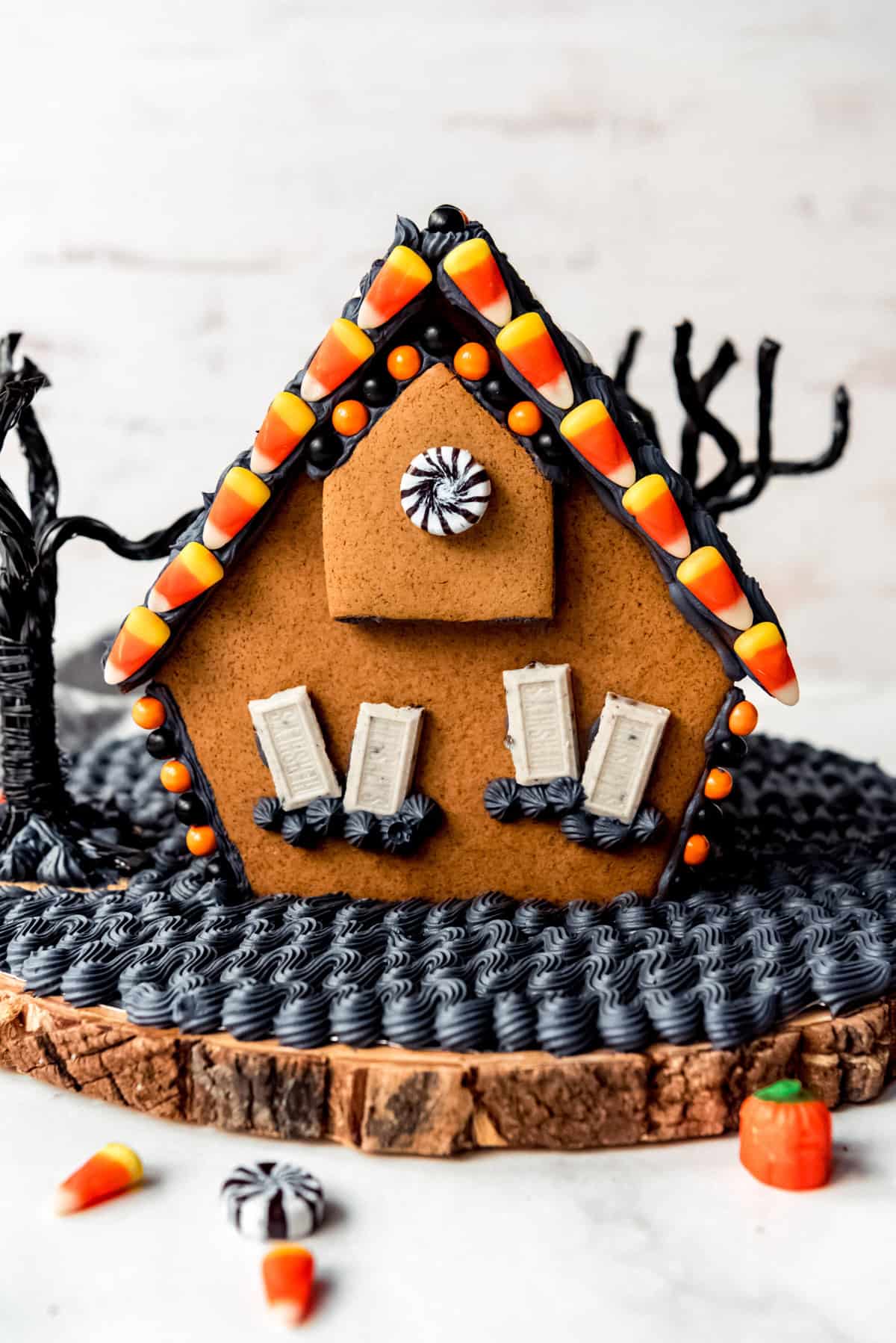 The back of a haunted gingerbread house decorated with candy corn and black royal icing.