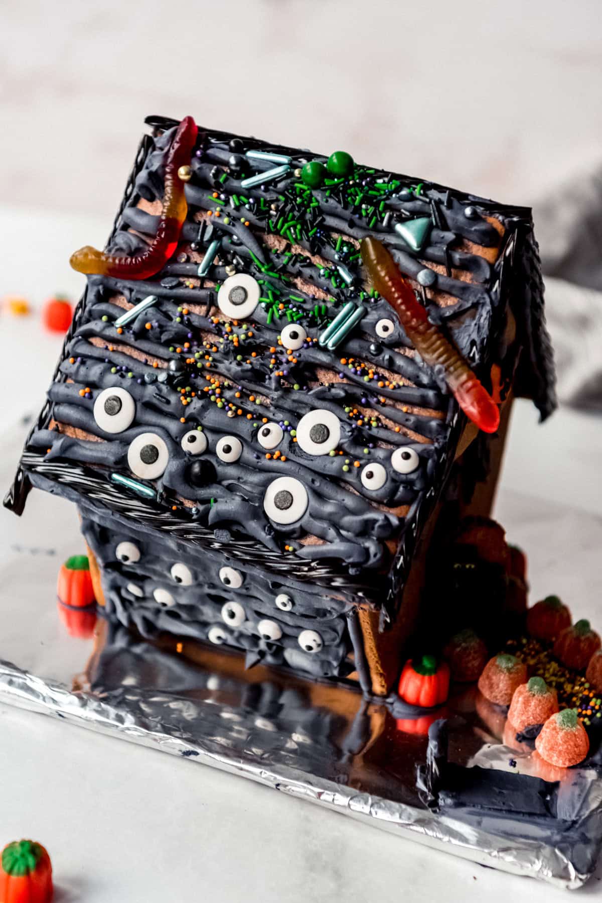 An image of a gingerbread house decorated with candy eyes and gummy worms.