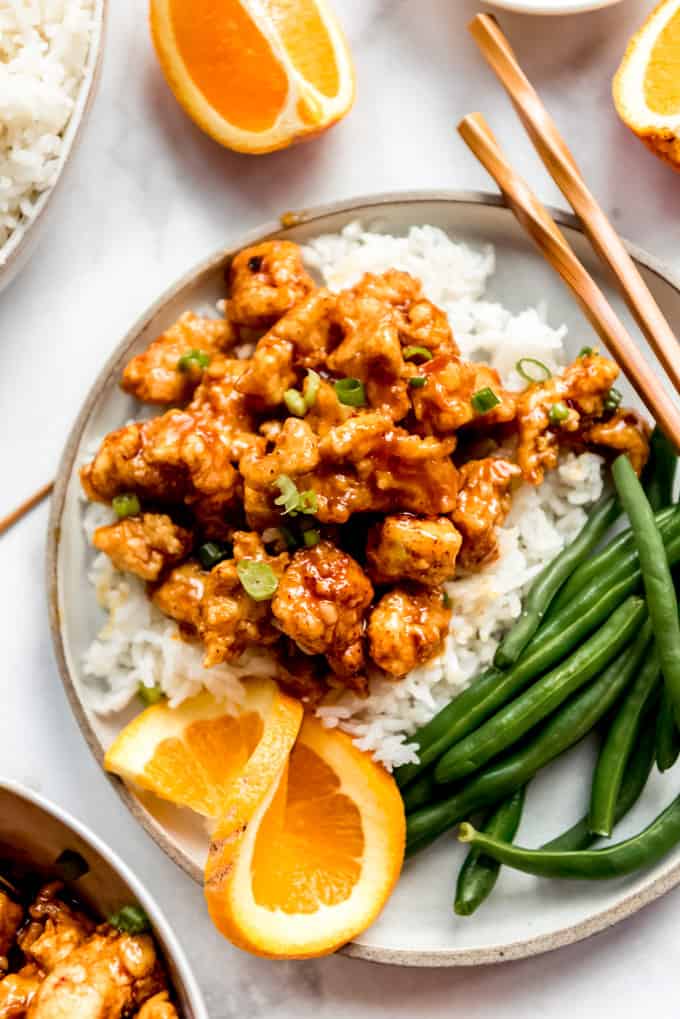 Orange Chicken on plate with green beans, rice and fresh orange