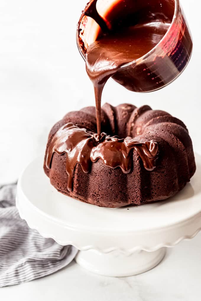 chocolate bundt cake with chocolate icing being poured over it