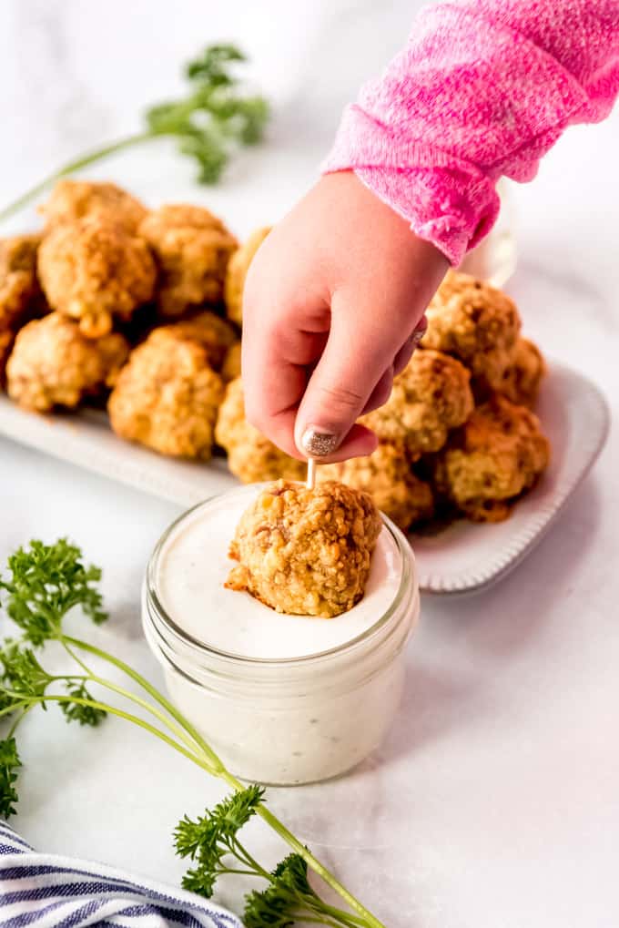 A sausage ball being dipped in ranch dressing.