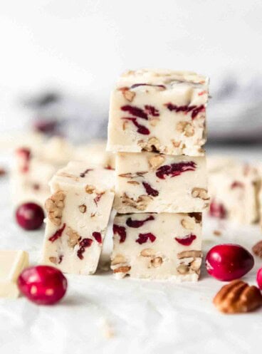 Pieces of white chocolate cranberry fudge stacked in a tower.