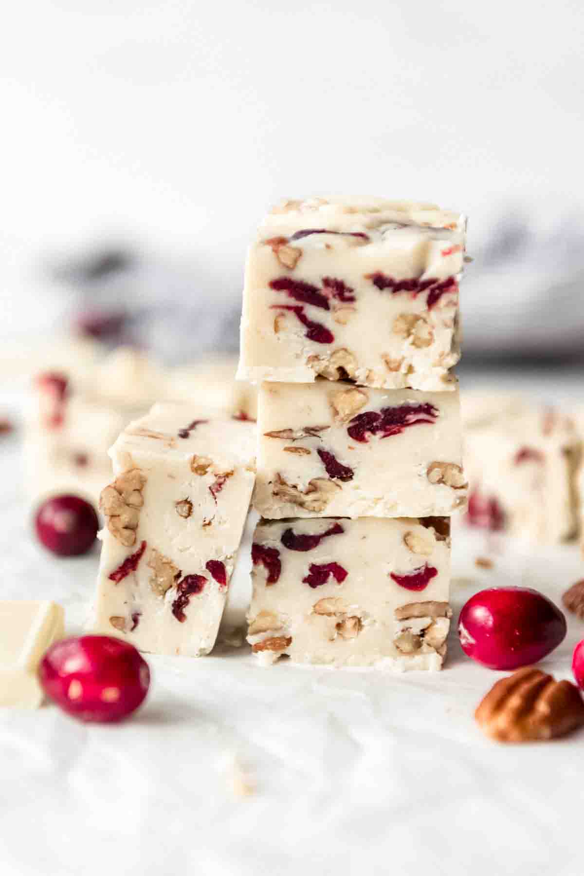 Pieces of white chocolate cranberry fudge stacked in a tower.