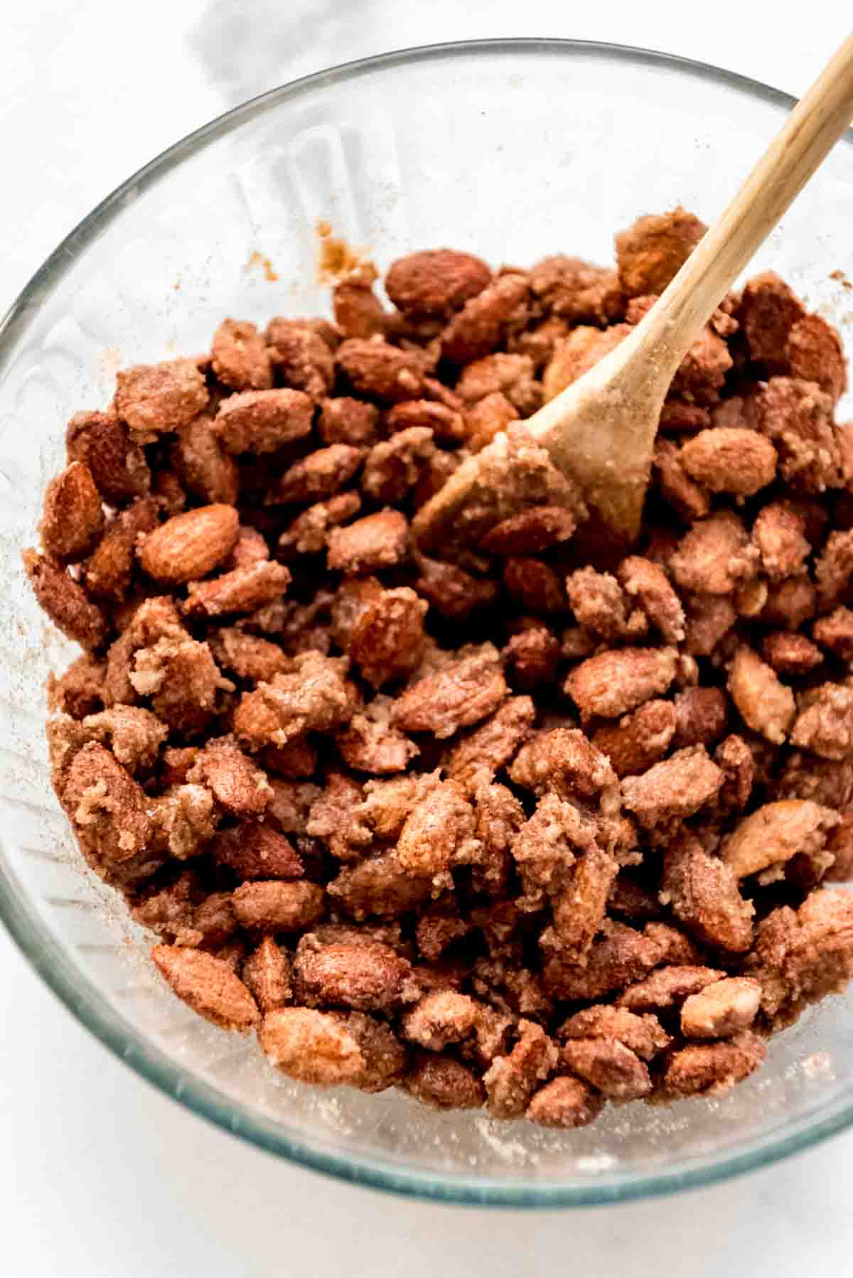 Almonds and other ingredients are well blended in a glass bowl. A wooden spoon is visible in the bowl. 