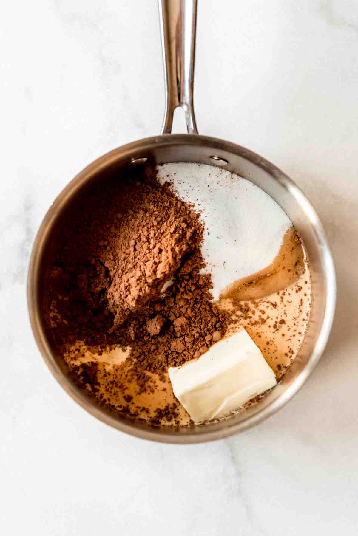 Ingredients for chocolate pecan pralines are placed in a metal pot.