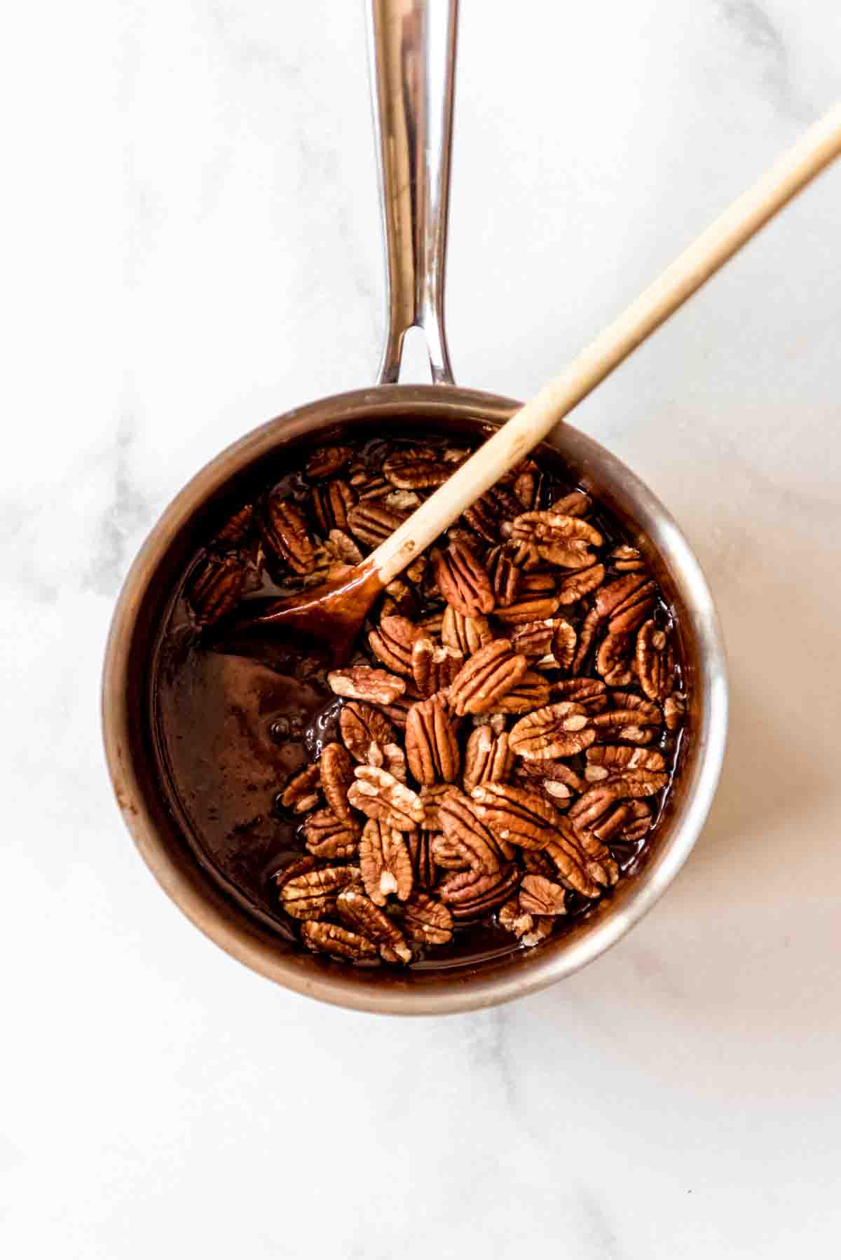 Adding whole pecans to make chocolate pecan pralines.