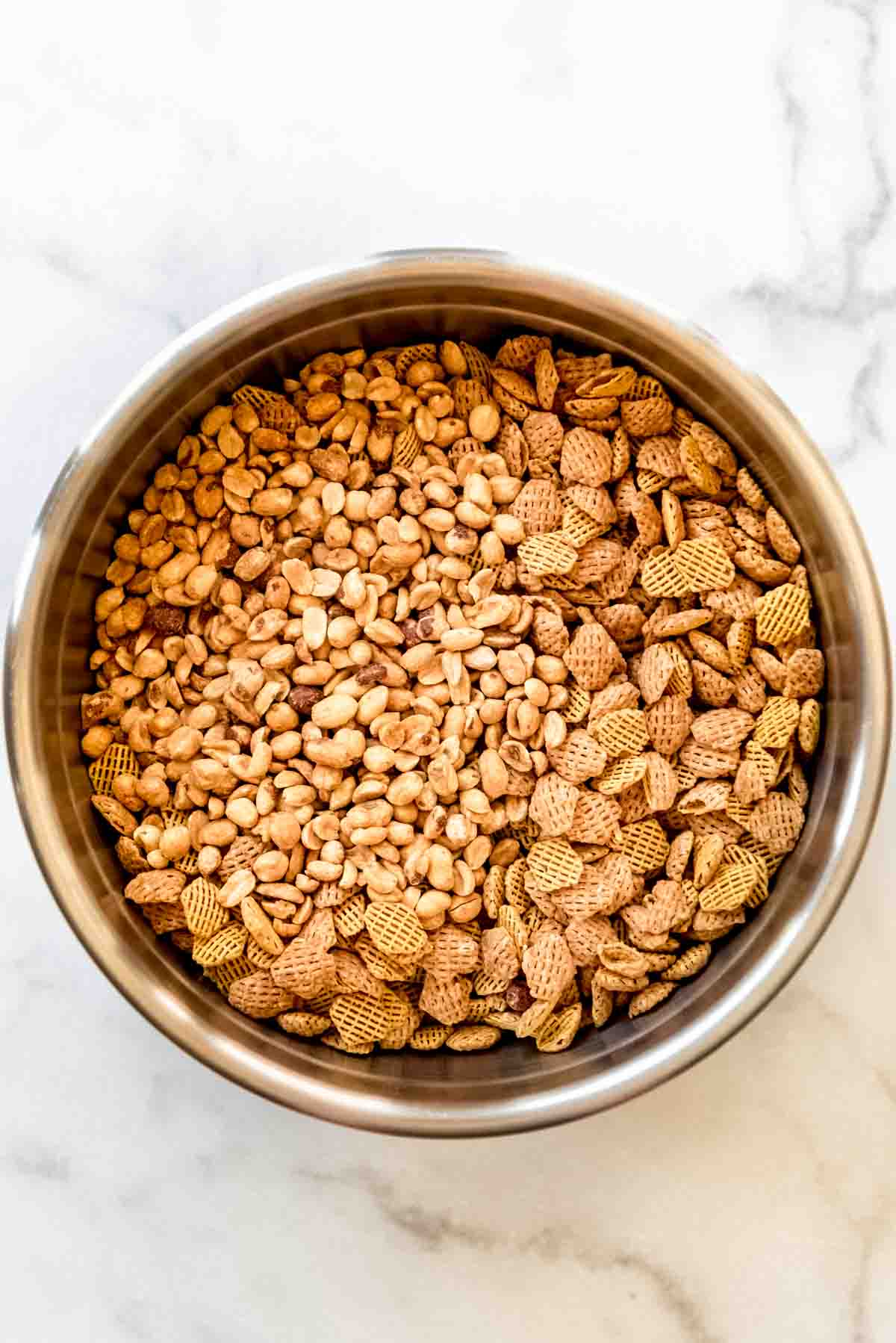 Cereal and peanuts are added to a large bowl. 