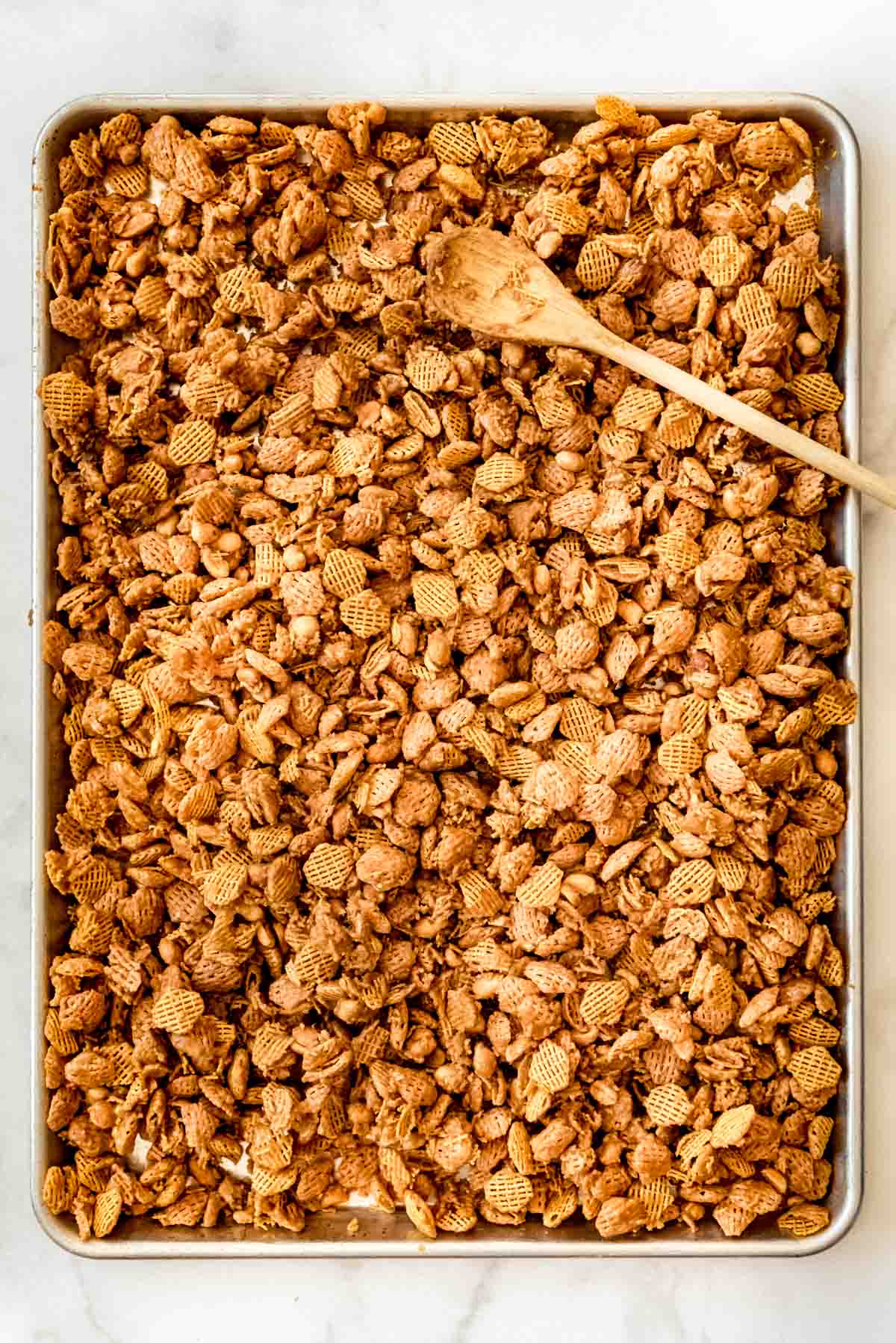 Cereal and peanut mixture is dumped onto a prepared baking sheet and spread out. 