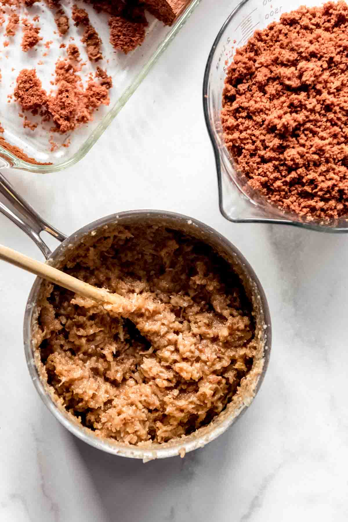 A pot of cooked coconut pecan frosting next to german chocolate cake crumbs.