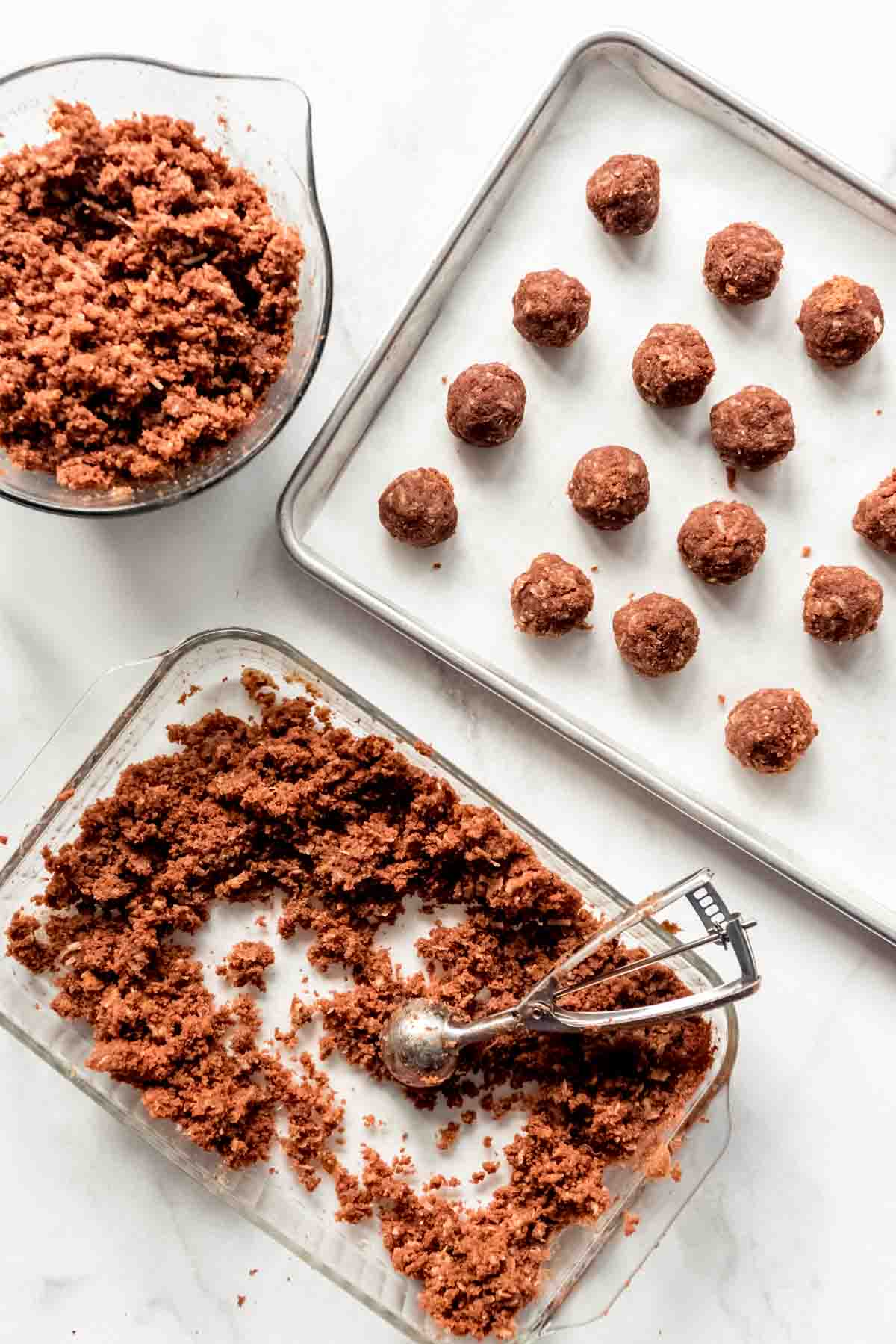 German chocolate cake base and frosting are scooped into balls and placed on a cookie sheet lined with parchment paper. 