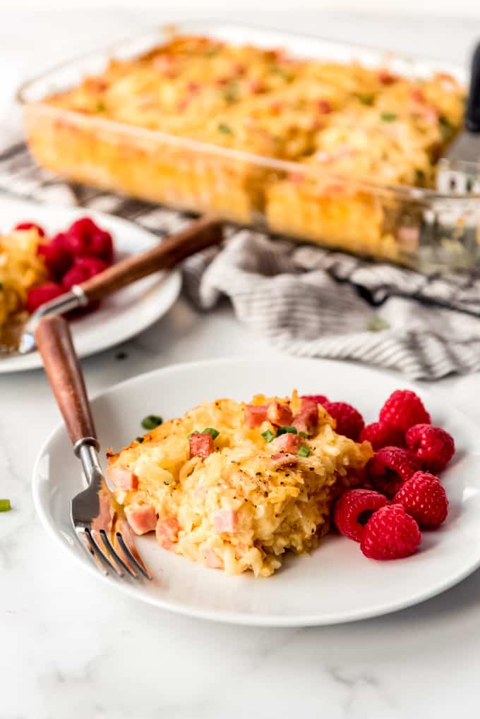 A slice of breakfast casserole on a plate with raspberries.