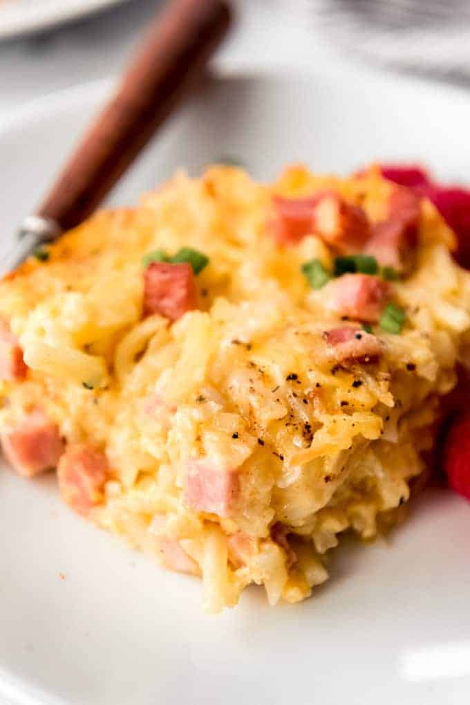 A slice of hashbrown breakfast casserole with ham on a white plate.