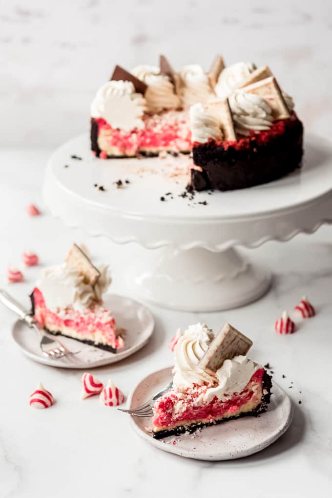 Slices of peppermint cheesecake in front of a cake stand.