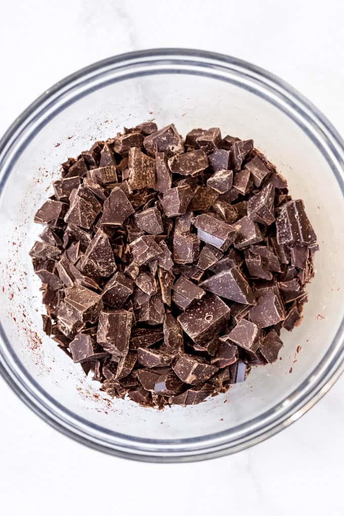Chopped dark chocolate in a glass bowl.