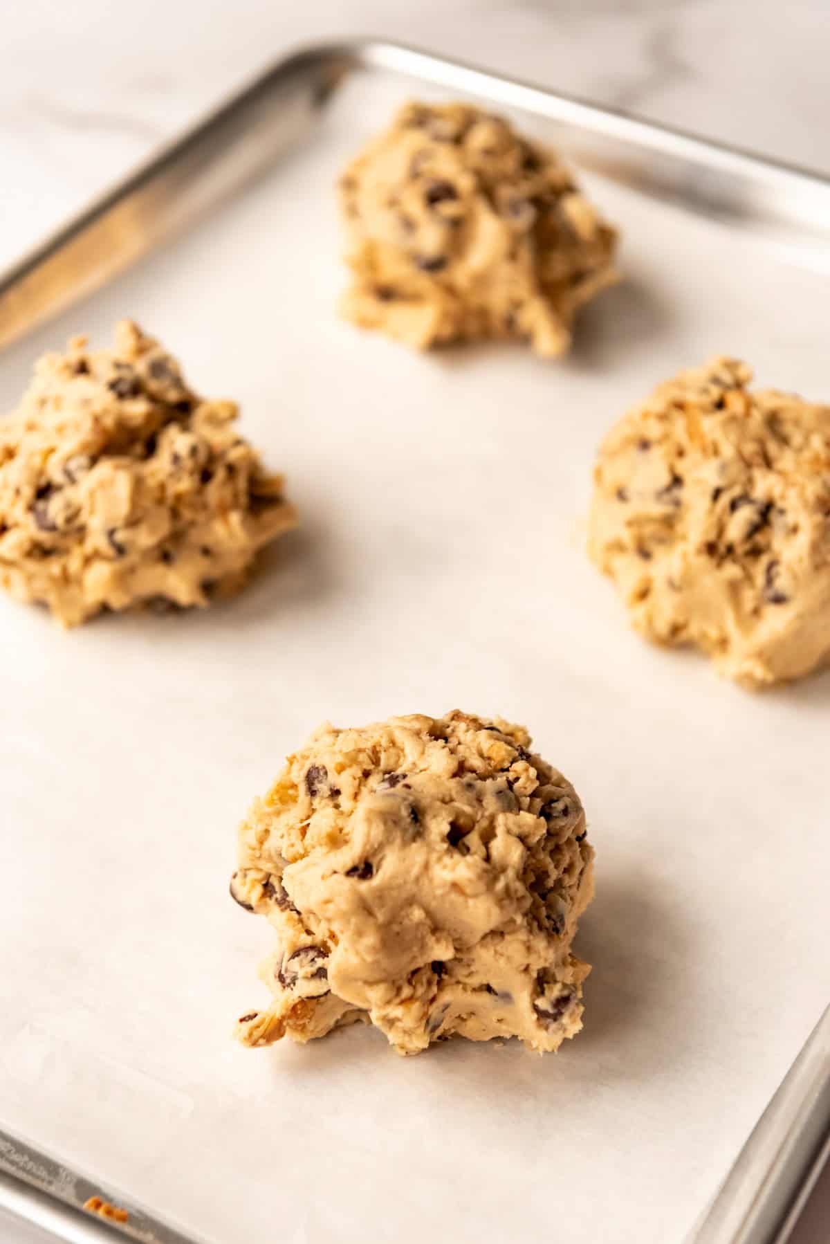 4 cookie dough balls on a baking tray, side