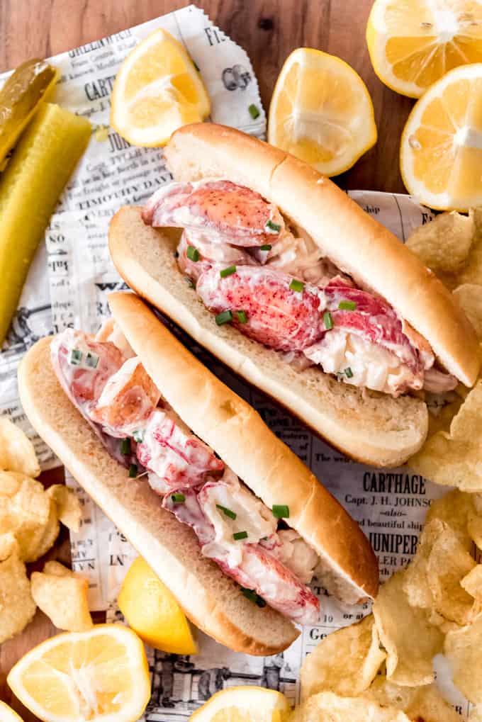 Two lobster roll sandwiches on newsprint.