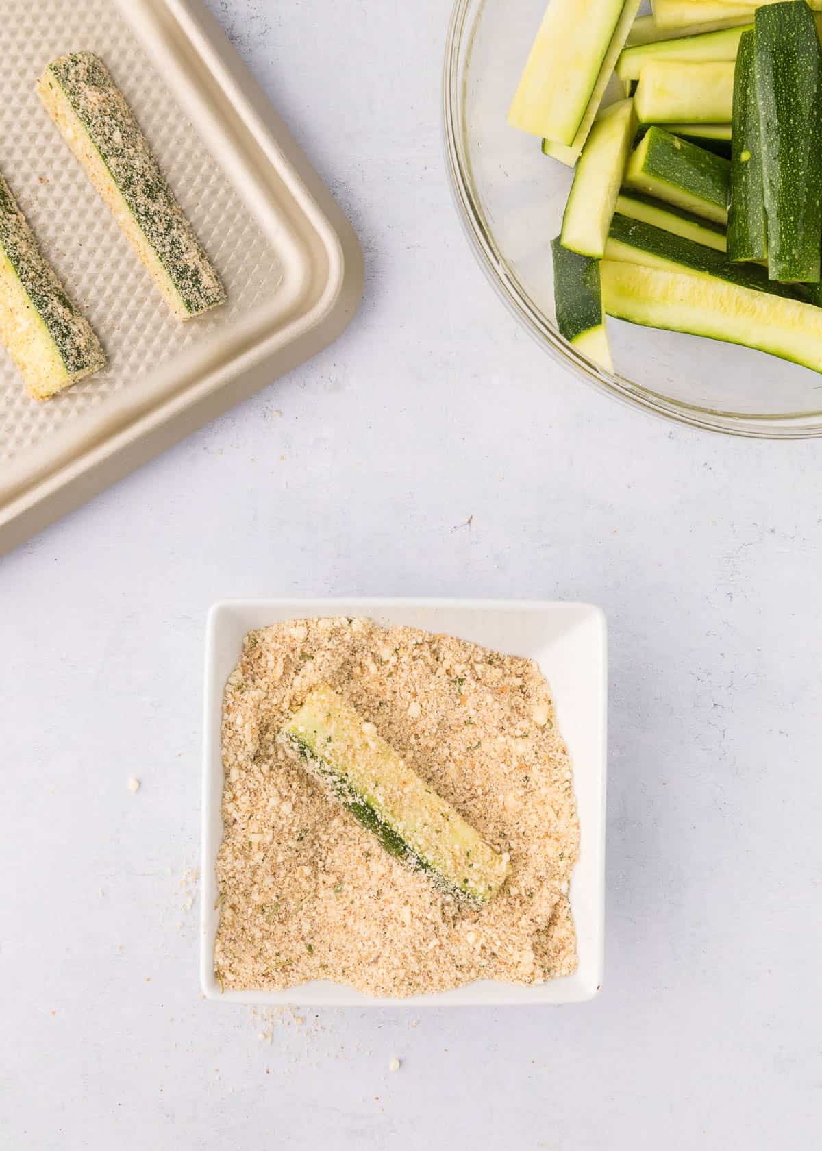 Coating zucchini fries in a seasoned parmesan mixture.