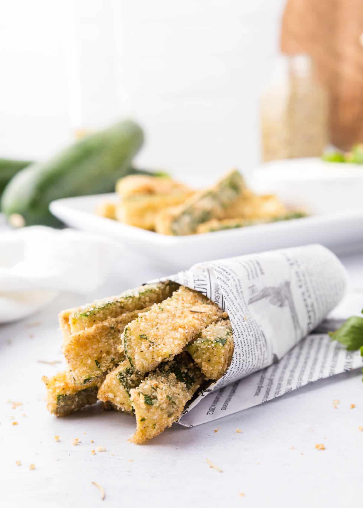 Parmesan zucchini fries wrapped in printed paper.
