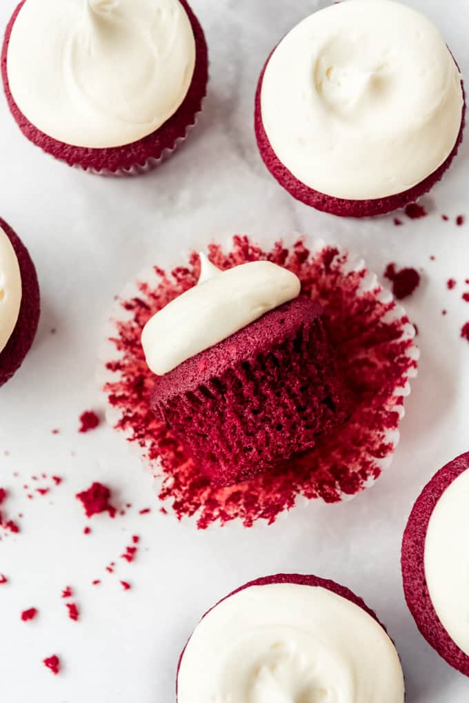 overhead Red velvet cupcakes with frosting on marble counter, one cupcake on it's side