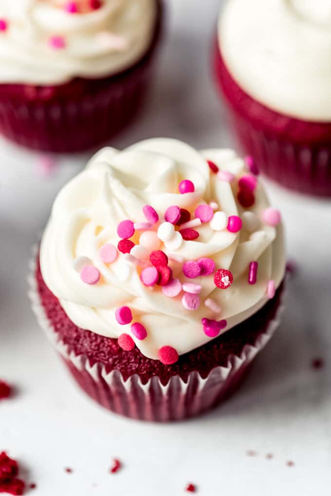 Red velvet cupcake with frosting and pink sprinkles on marble counter