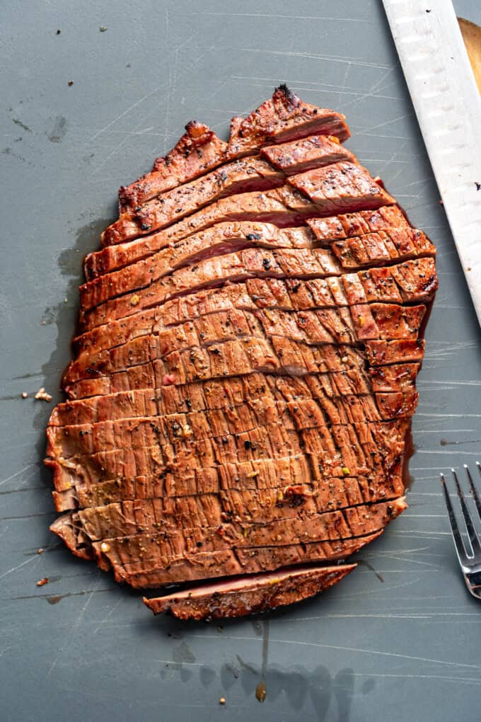 Flank steak sliced against the grain on a cutting board.