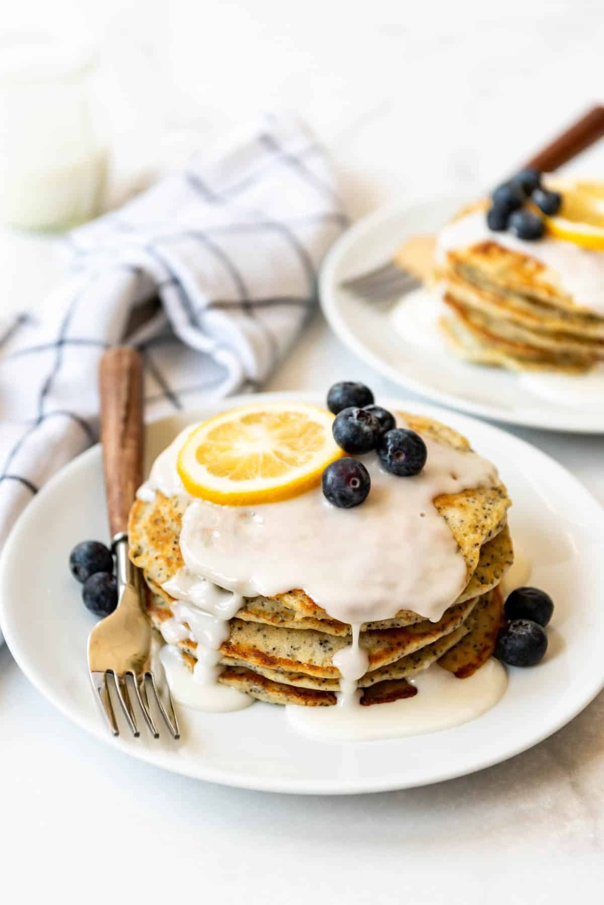 A stack of pancakes with lemon glaze and blueberries.