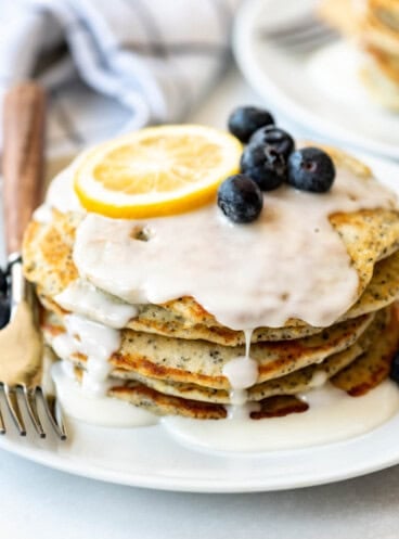 An image of lemon poppy seed pancakes stacked on a plate.