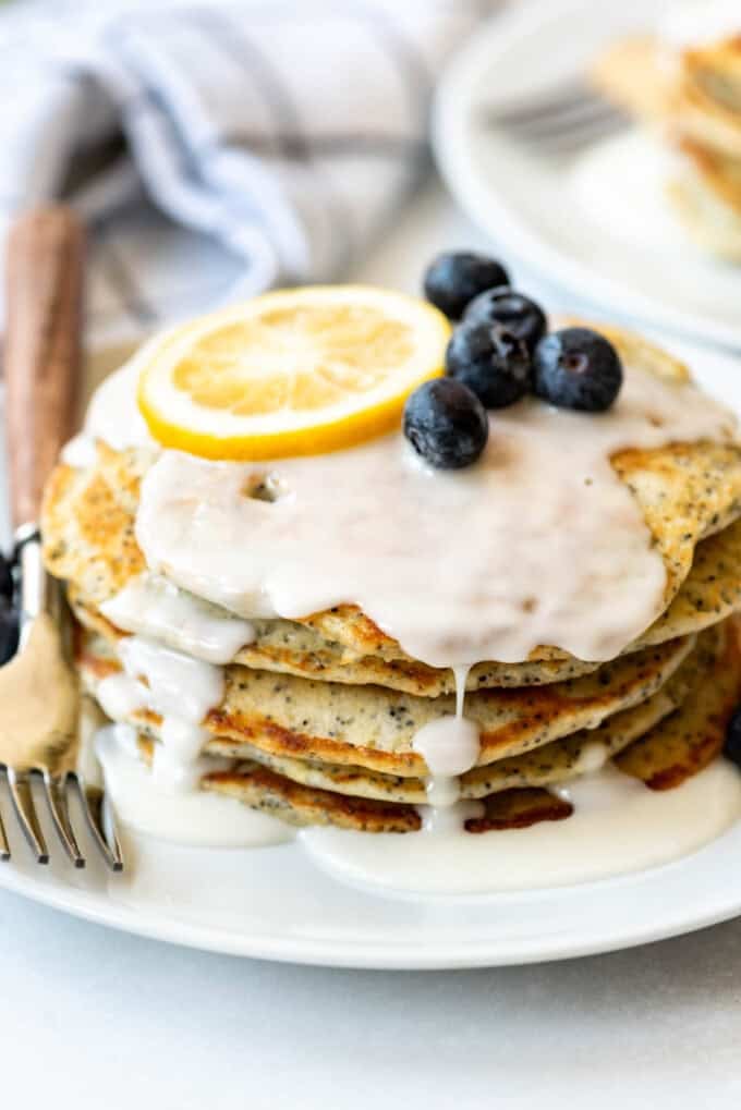 An image of lemon poppy seed pancakes stacked on a plate.